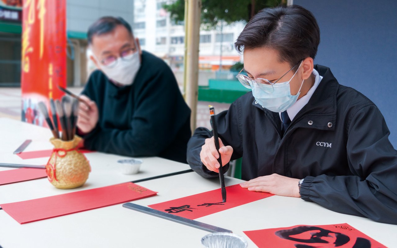 跟校長一樣熱愛書法,而且是多項比賽得獎者的李兆豐同學在社區送贈揮春。